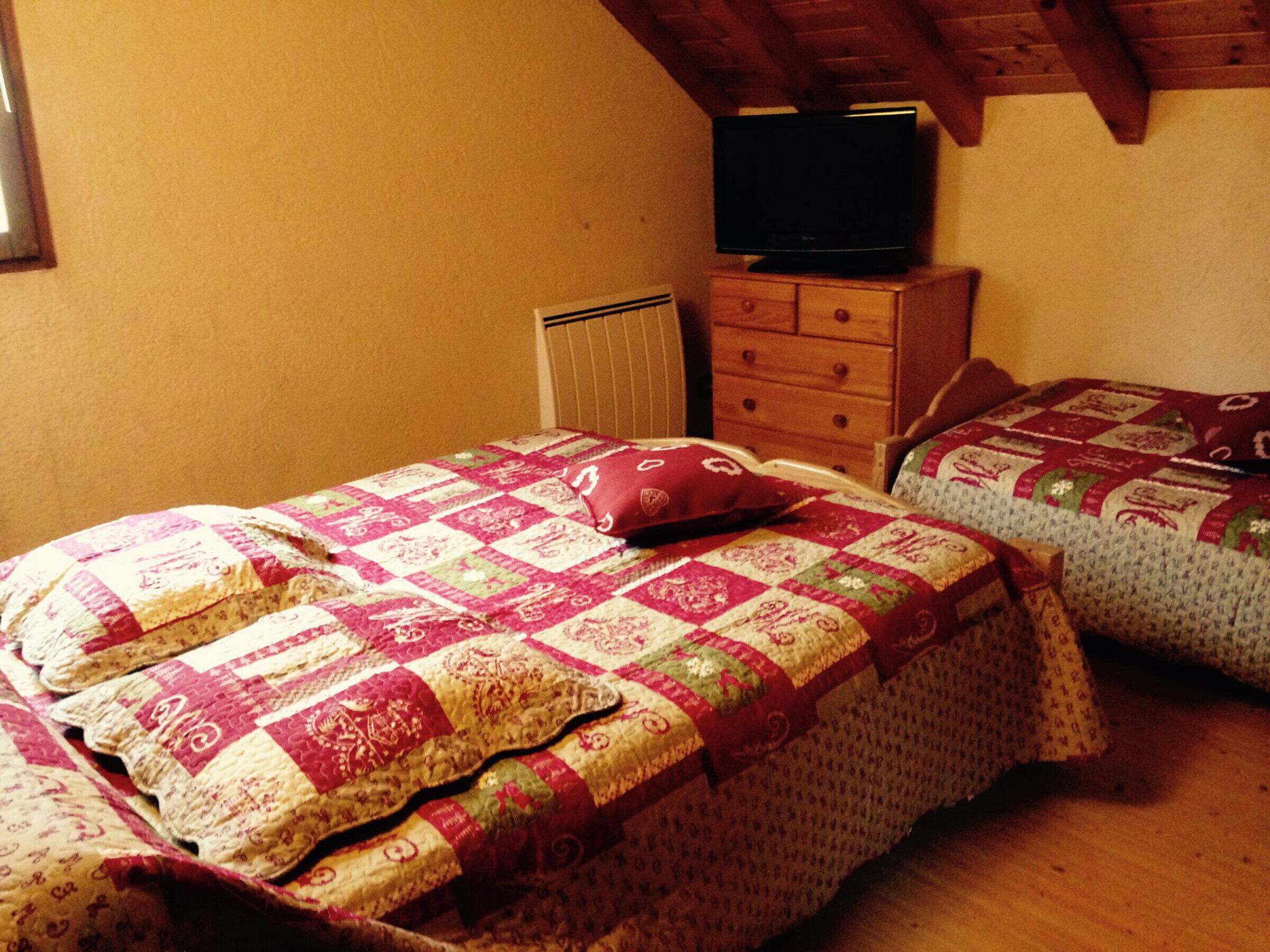 Een slaapkamer met twee bedden, een kapstok en een televisie.