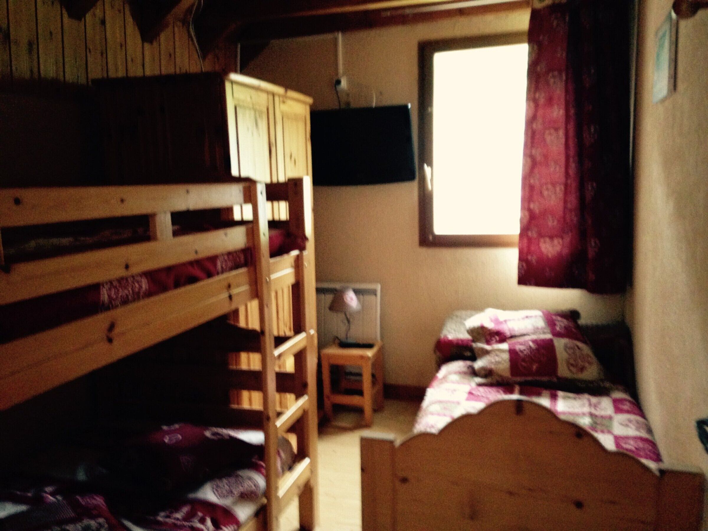 Une chambre avec un lit superposé, une télévision et une petite table.