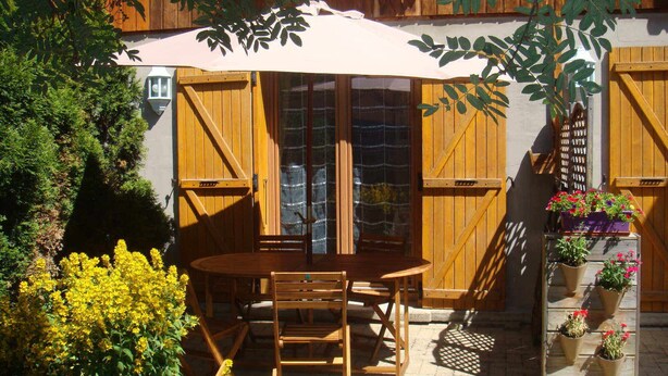 A wooden outdoor seating area with a table and chairs, surrounded by potted plants and a wooden fence. - Duplex 3 rooms 4 people, south-facing terrace, private parking (Valloire)
