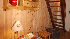 A wooden room with a loft bed, a red cup on a shelf, a table with magazines, and a heart-shaped lamp. - Duplex 3 rooms 4 people, south-facing terrace, private parking (Valloire)