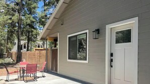 A building with a white door, a window, and a small outdoor seating area with chairs.