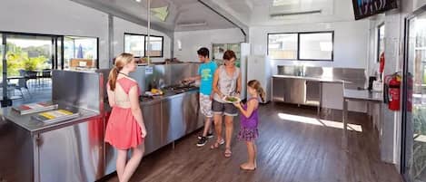A modern kitchen with stainless steel appliances, a service counter, and a television screen.