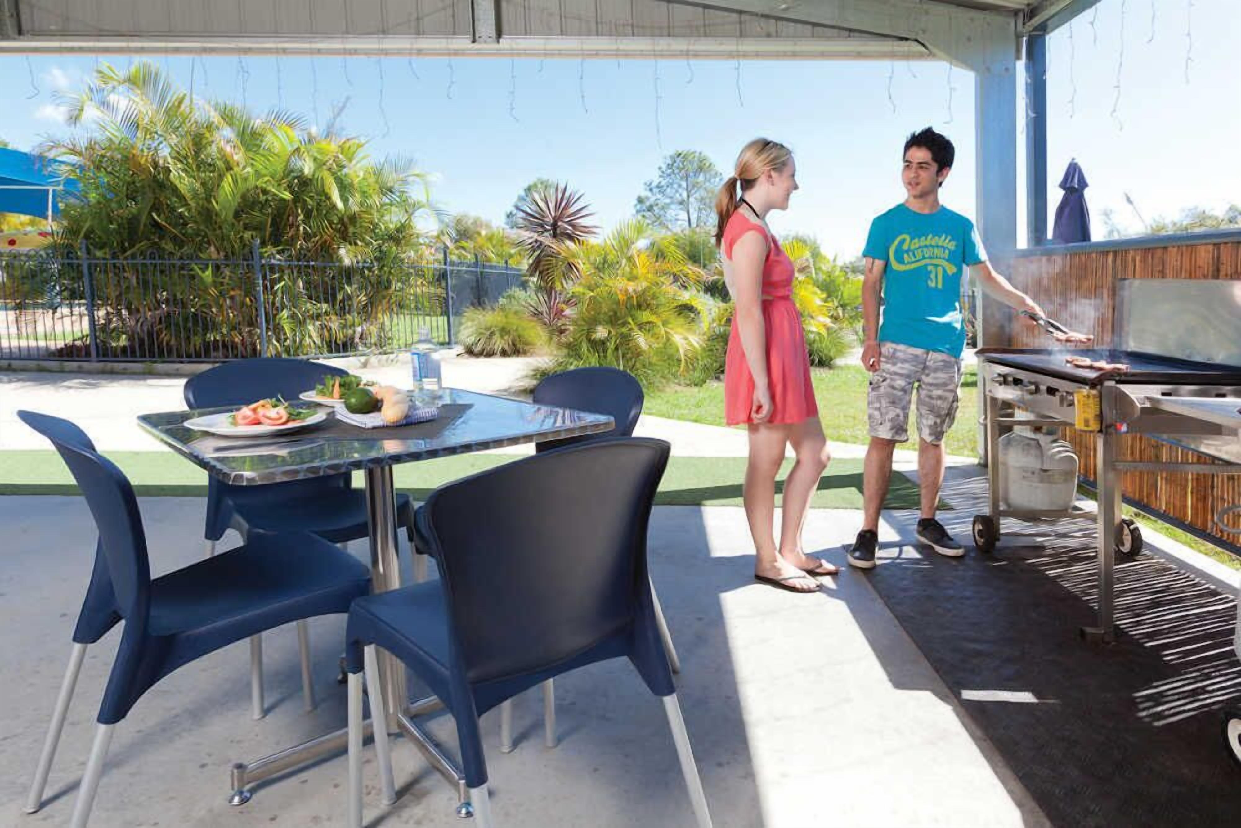 An outdoor patio with a grill, dining table, and chairs.