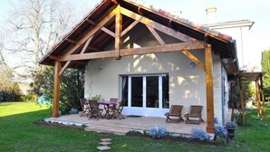 Un portico coperto con tavolo e sedie, un giardino e un edificio con tetto a falda.