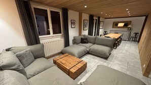En moderne stue med en hjørnesofa, et træsofabord og et spiseområde med et træbord og stole.