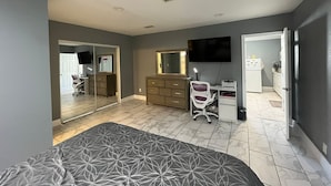 Un dormitorio con cama, cómoda, televisor y escritorio con silla.
