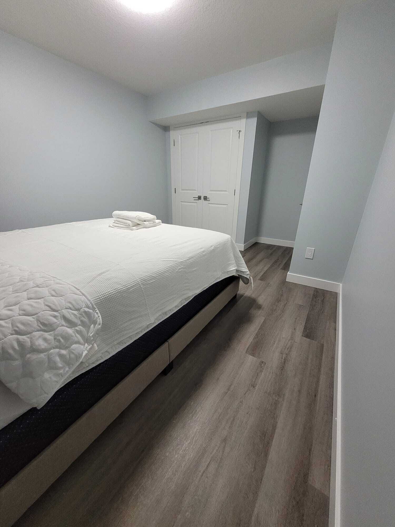A bedroom with a bed, a wardrobe, and a door leading to another room.