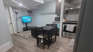 A modern kitchen with a dining area, featuring a flat-screen TV, wooden flooring, and a built-in oven.