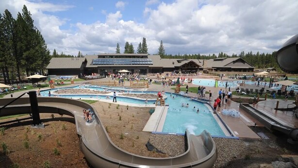 Een waterpark met verschillende zwembaden, glijbanen en een groot gebouw op de achtergrond.
