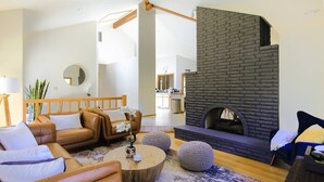 Een moderne woonkamer met leren banken, een ronde salontafel en een stenen openhaard.