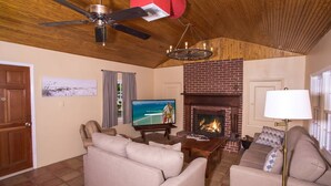 Un salon avec une cheminée, un téléviseur et un ventilateur de plafond.