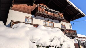 Un chalet traditionnel doté de balcons en bois et d’un toit enneigé.