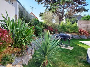 Un jardín cuidado con diversas plantas y una parrilla.