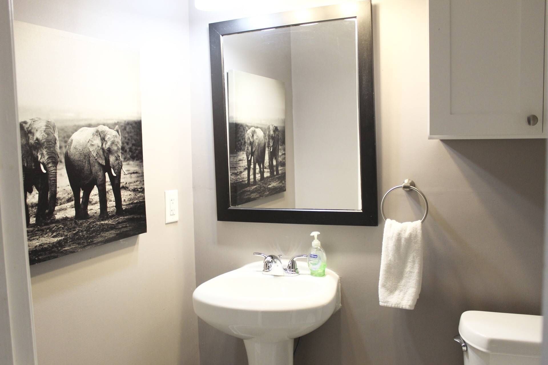 A bathroom with a white sink, a mirror, a toilet, and a towel rack.