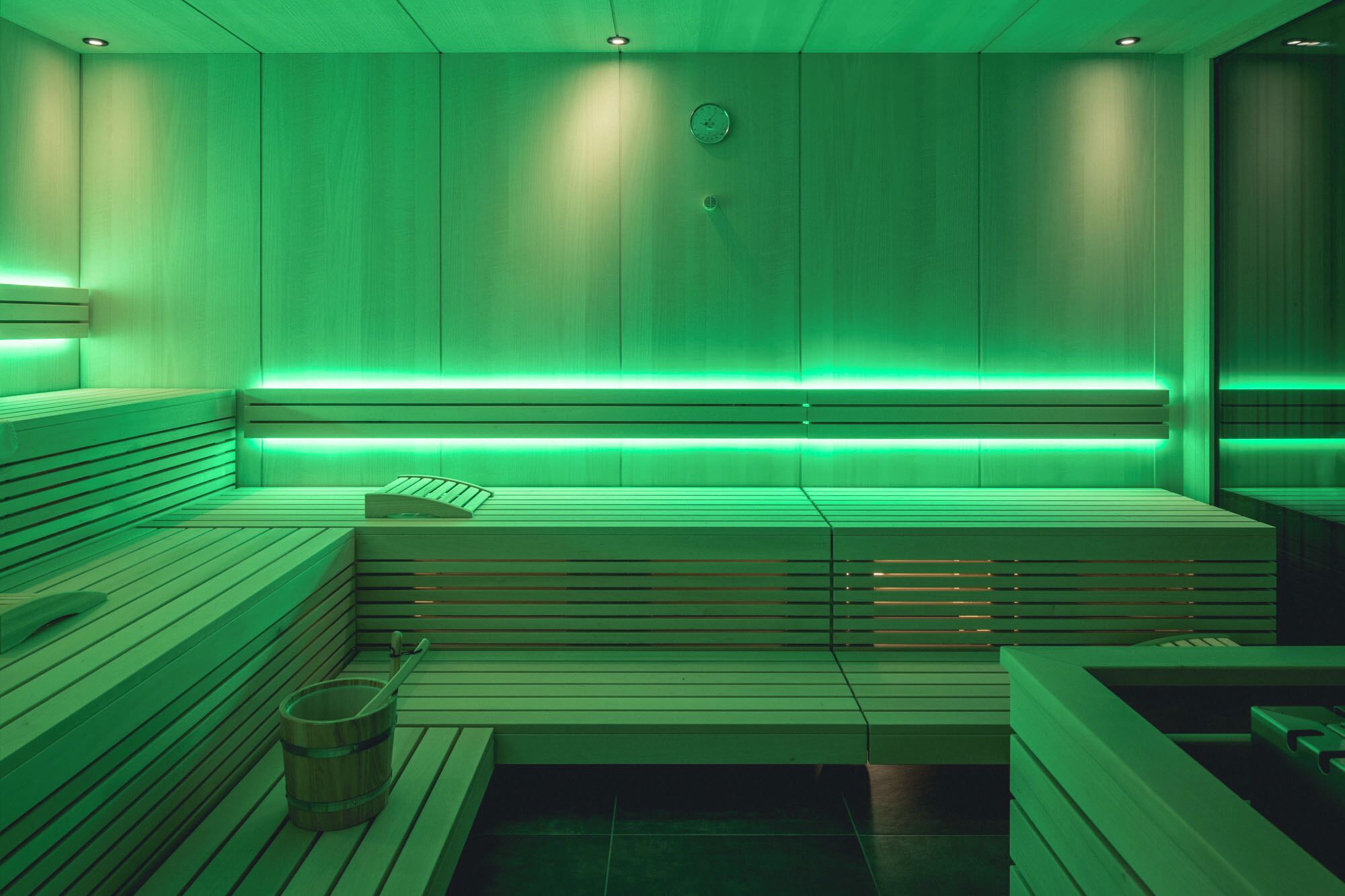 A sauna with wooden benches and a green-lit ceiling.