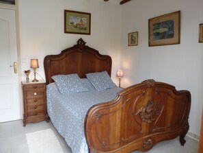 A bedroom with a wooden bed, two bedside tables with lamps, a dresser, and framed pictures on the wall. - A vacation rental in a haven of unspoiled nature. Horse Boarding, Hall Rentals  (Saint-Ferriol)