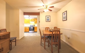 A dining area with a table and chairs, a kitchen in the background, and a ceiling fan. - Official Seasons RMC Condo 17D- 2 Bedrooms - Sleeps 6 - No Fees (Bartlett)