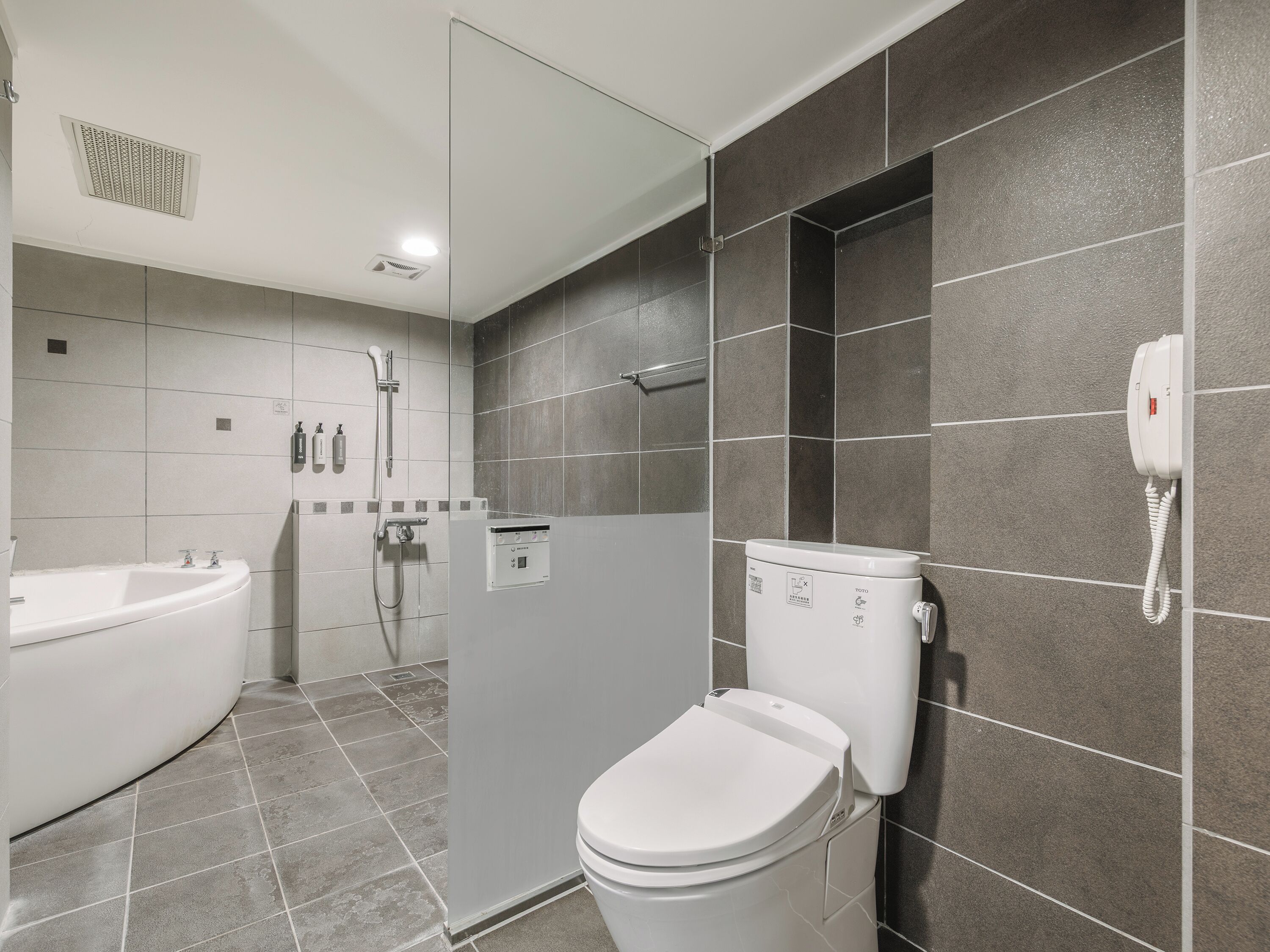 A modern bathroom with a bathtub, toilet, and shower.