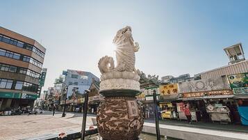 A traditional Chinese lion statue in a public square with modern buildings in the background.