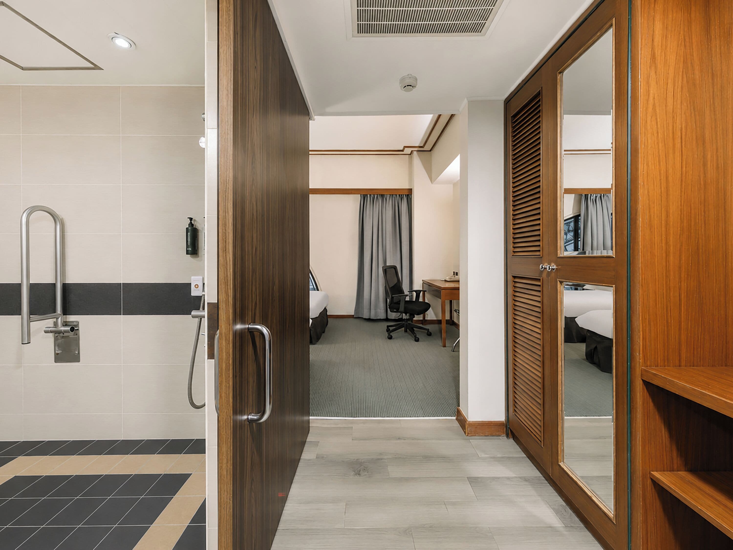 Une chambre d’hôtel équipée d’une douche, d’un bureau, d’une chaise, d’un lit et d’une armoire.