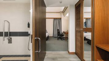 Une chambre d’hôtel équipée d’une douche, d’un bureau, d’une chaise, d’un lit et d’une armoire.