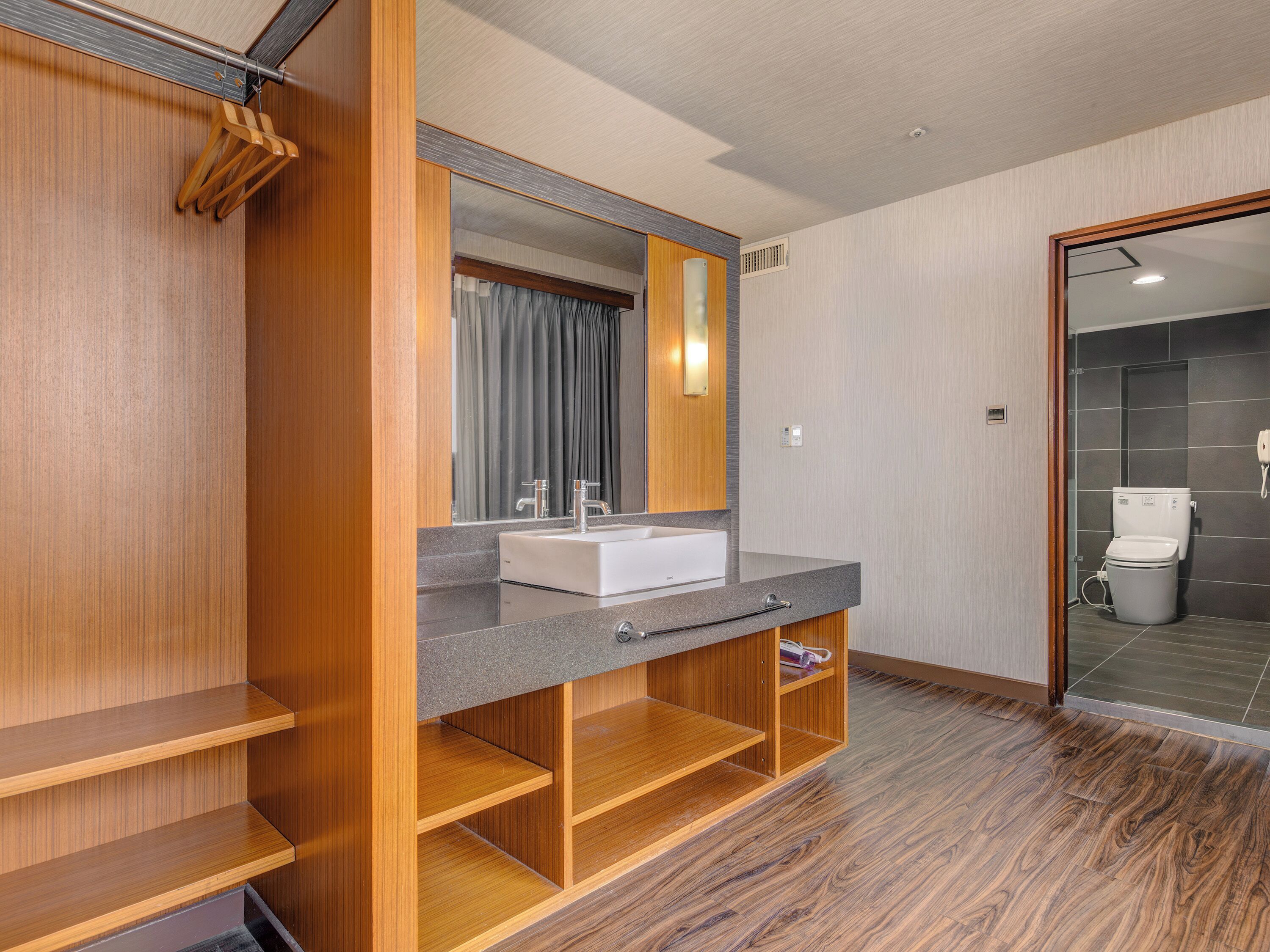 Un baño moderno con tocador, espejo y estanterías de madera.