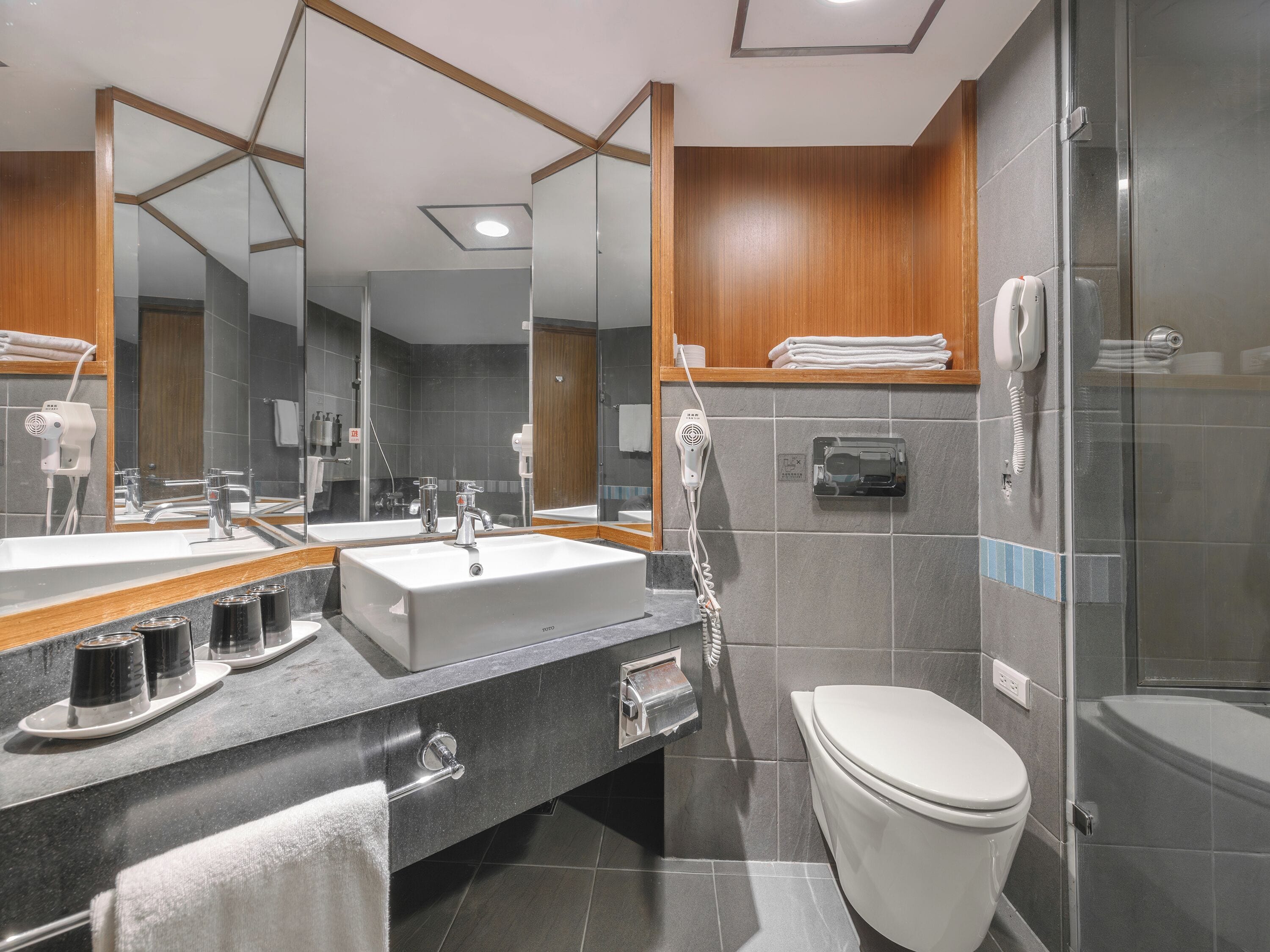 A modern bathroom with a large mirror, a sink, a toilet, and a shower area.