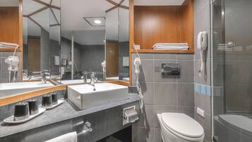A modern bathroom with a large mirror, a sink, a toilet, and a shower area.