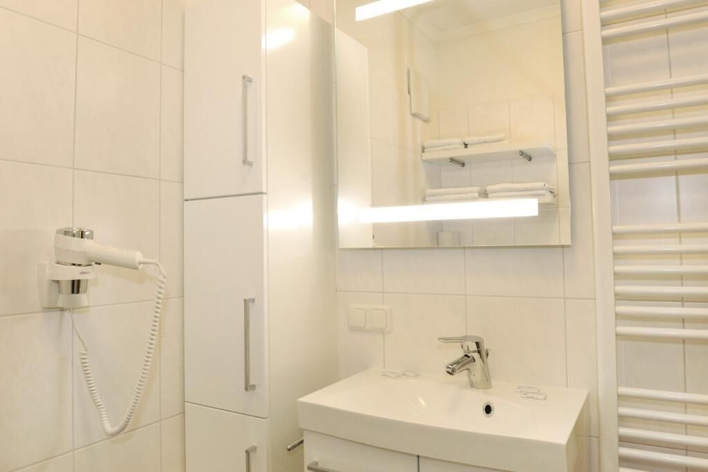 A modern bathroom with a white sink, a mirror, and a towel rack.