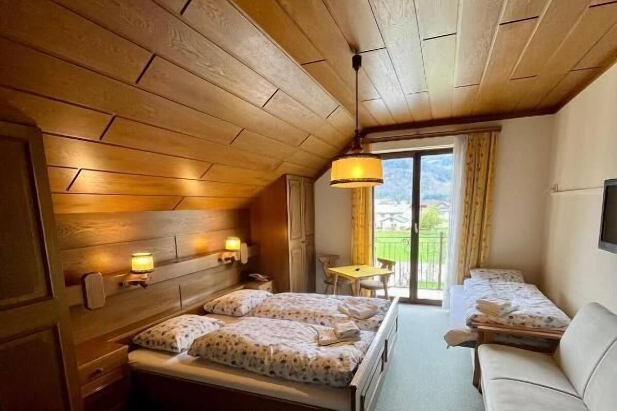 Una habitación acogedora con paneles de madera, una cama, un sofá y una mesa con lámpara.