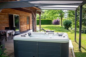 Une cabane en bois avec un jacuzzi, un espace salon extérieur et un jardin.