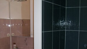 A compact bathroom with a washing machine, a sink, and a mirror.