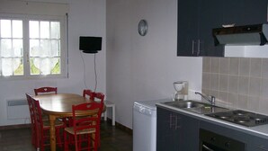 A compact kitchen with a dining table and chairs, a coffee maker, a dishwasher, and cabinets.