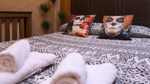 Ein Bett mit gemusterten Bettbezügen, zwei Zierkissen und zusammengerollte Handtücher.