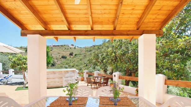 Un espace extérieur aménagé pour les repas, avec des tables et des chaises, offrant une vue sur une colline.