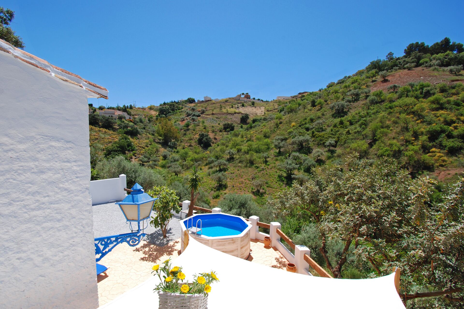 Un espace piscine avec une piscine bleue, des murs blancs et une vue sur une colline.