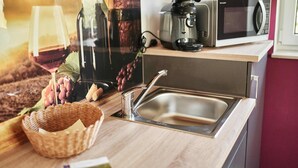 A kitchen counter with a sink, a microwave, a wine glass, and a basket of grapes. - Appartment mit Panorama Blick (Stadecken-Elsheim)