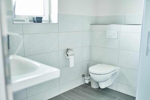 Un bagno moderno con il water, un lavandino e una finestra sopra di esso.