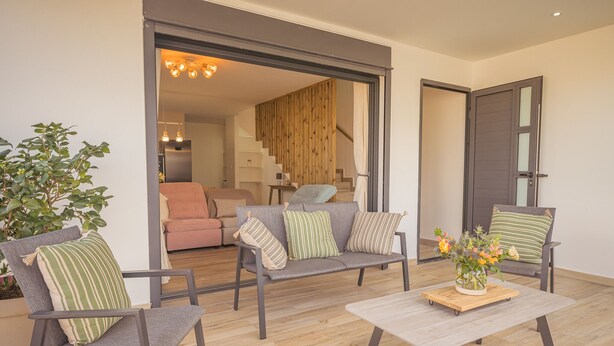 A modern living room with a grey sofa set, a coffee table with a vase of flowers, and a wooden floor. - Charming villa between sea and mountains, ideal for friends or family (Saint-Louis)