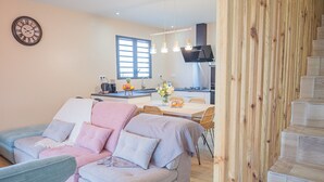 A modern living room with a sofa, a dining table, and a kitchen in the background. - Charming villa between sea and mountains, ideal for friends or family (Saint-Louis)