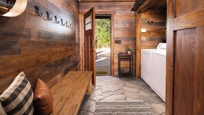 A wooden interior with a bench, a door leading outside, and a laundry area.