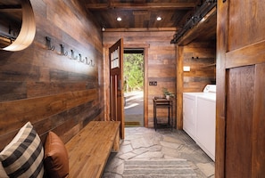 Cozy interior space with a bench and hooks, perfect for hanging belongings. A doorway leads to an outdoor area and laundry facilities are available.
