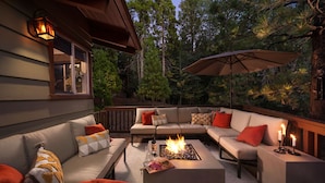 A cozy outdoor seating area with a fire pit, comfortable sofas, and a large umbrella.
