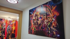 Une pièce avec une grande fresque murale représentant une scène de film, une table ronde avec un magazine et un luminaire au plafond.