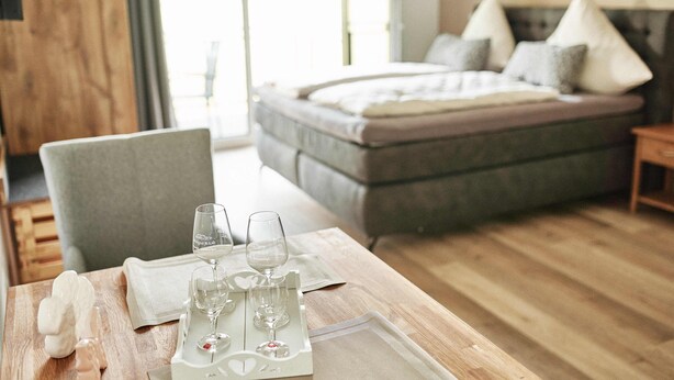 A neatly arranged dining table with a white tray holding wine glasses and a decorative item, set against a wooden floor. - White wine apartment with panoramic view (Stadecken-Elsheim)