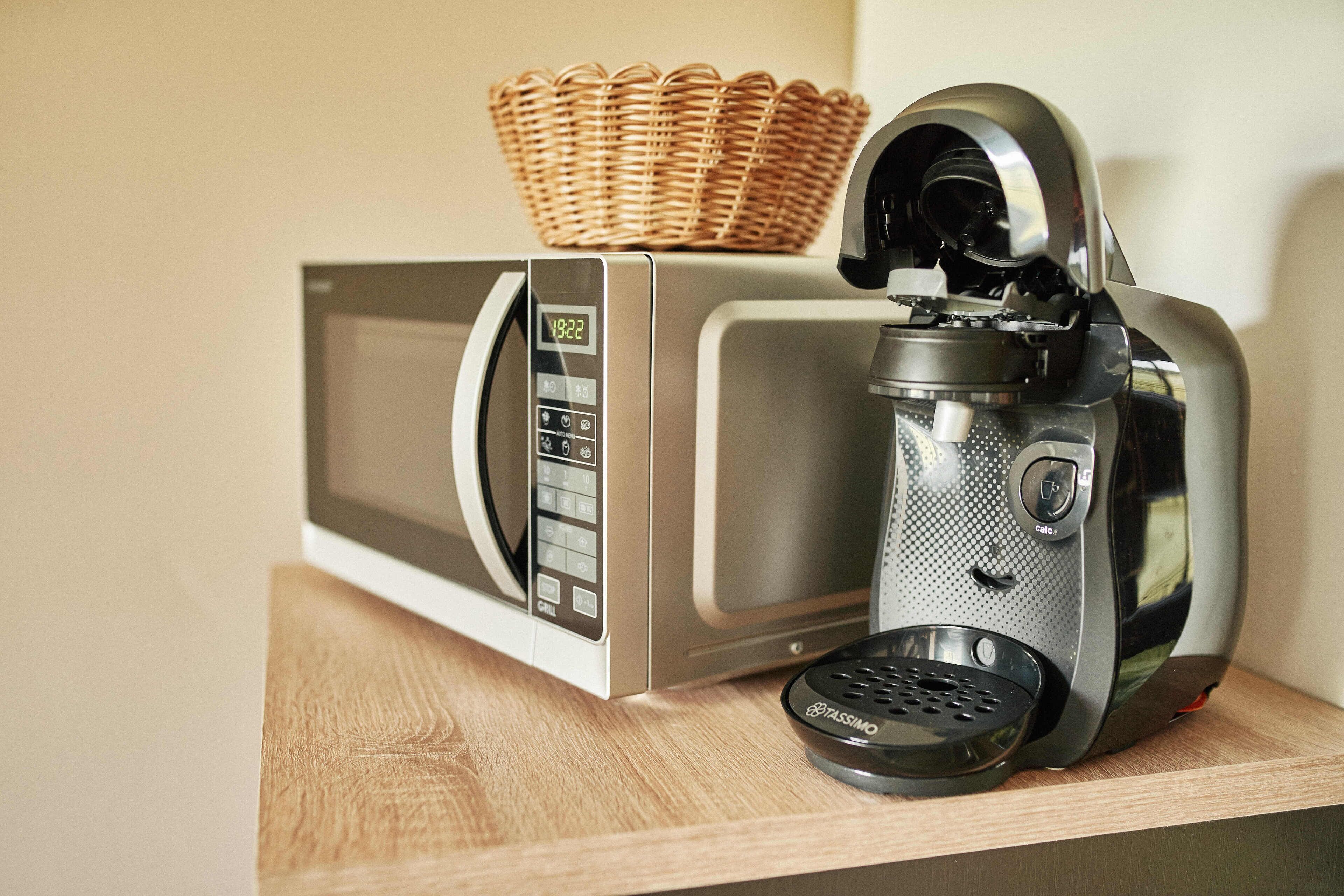 Eine Mikrowelle und eine Kaffeemaschine auf einer Holztischplatte.