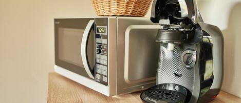 Eine Mikrowelle und eine Kaffeemaschine auf einer Holztischplatte.