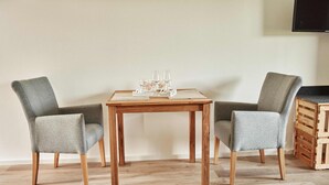 A dining area with a wooden table and two grey upholstered chairs. - White wine apartment with panoramic view (Stadecken-Elsheim)