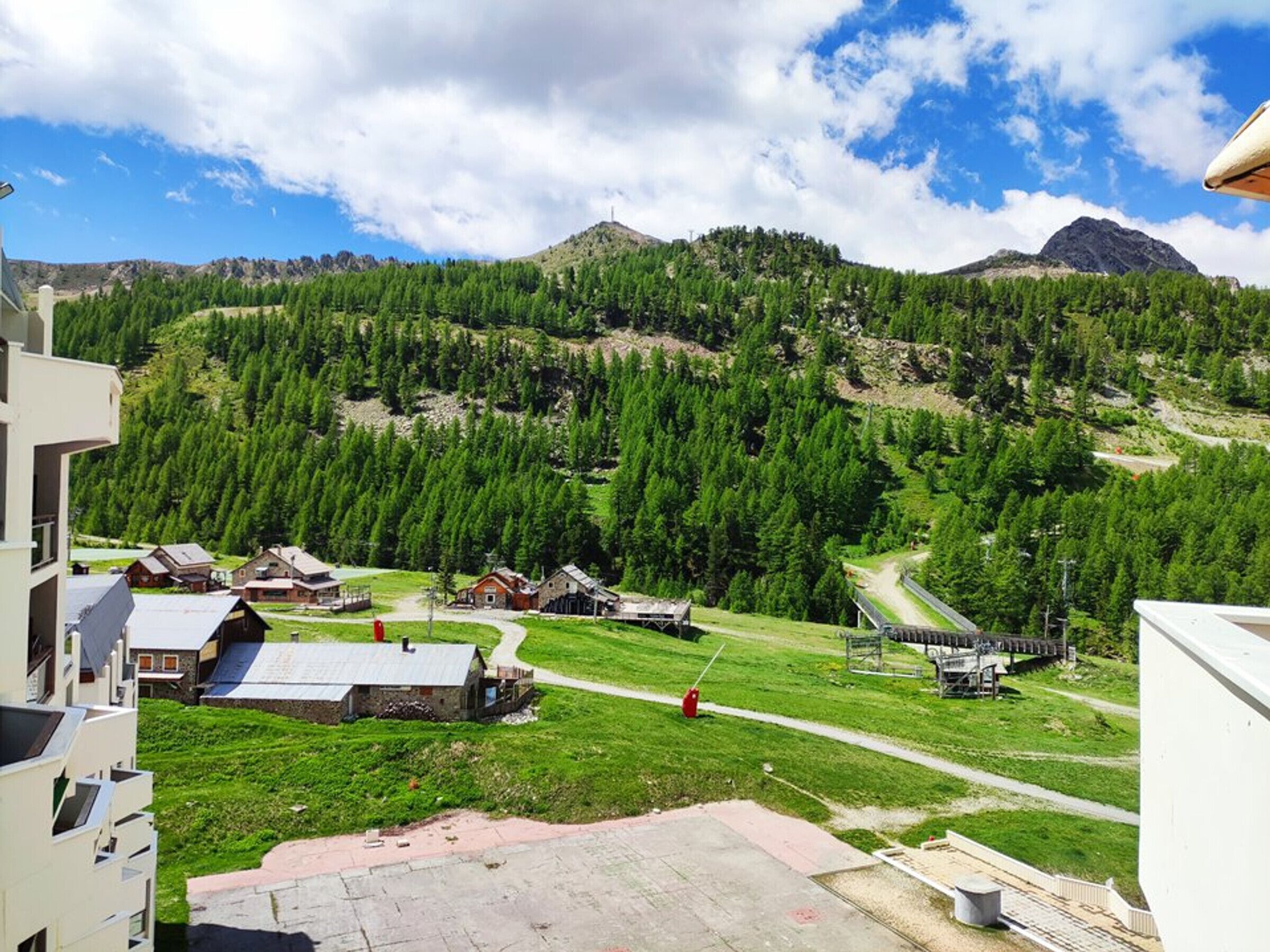 Eine Berglandschaft mit blauem Himmel, einer Straße und mehreren Gebäuden im rustikalen Stil.