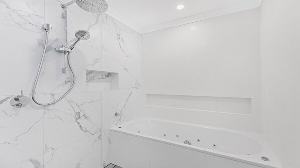 A modern bathroom with a marble wall, a freestanding bathtub, and a shower with a handheld showerhead. - SERENDIPITY - THE VINTAGE HOLIDAY HOUSES (POKOLBIN)